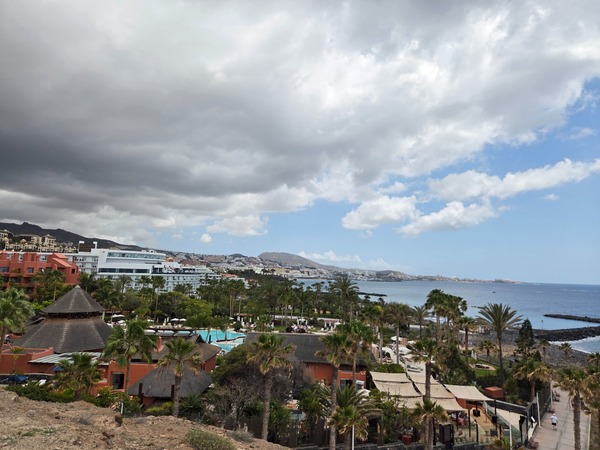 Vista panorámica de la costa de Costa Adeje con hoteles, palmeras, mar y nubes sobre el sur de Tenerife.