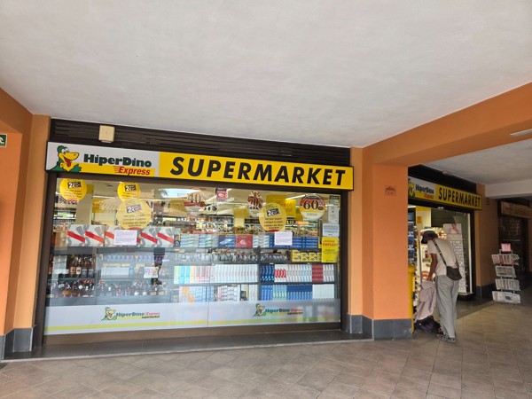 Entrada de supermercado HiperDino Express en Costa Adeje con escaparate de productos, ofertas visibles y acceso lateral.