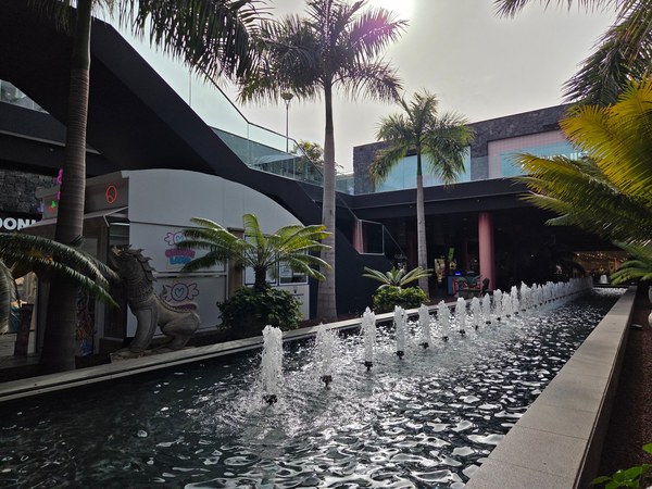Zona interior de Siam Mall con una larga fuente, palmeras y locales comerciales alrededor.